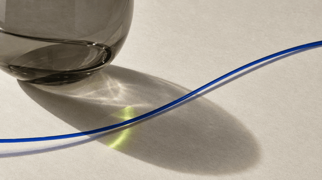 Translucent smoked glass and a curved blue strand resting over paper.